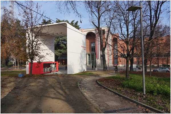 Passeggiando intorno al palazzo della Triennale si percepisce il violento impatto del volume della Biglietteria sulla facciata per effetto ostruttivo e per estraneità dimensionale e formale. Un rapporto ben diverso da quello rappresentato sul cartello del cantiere.